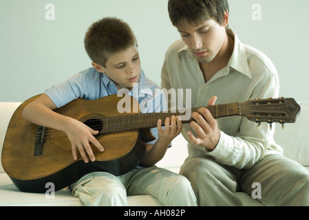 Man teaching boy to play the guitar