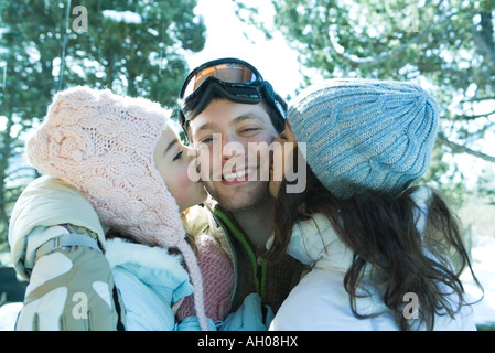 Young man in ski gear being kissed on cheeks by two young females Stock Photo