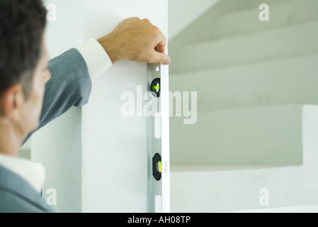 Man holding level against to wall, focus on level Stock Photo