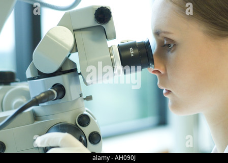 Young female scientist looking through microscope, extreme close-up Stock Photo