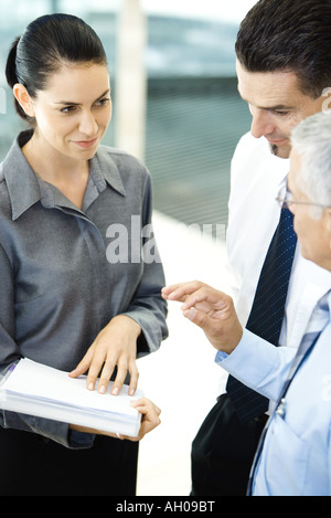 Young businesswoman holding file, chatting with male associates Stock Photo