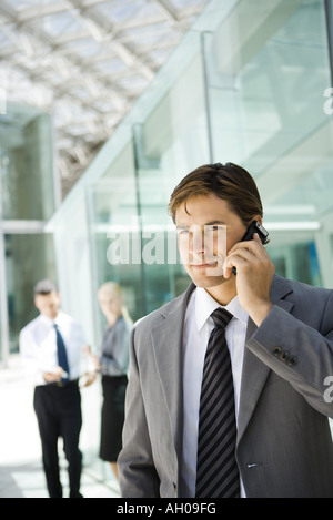 Young businessman using cell phone, looking away, portrait Stock Photo