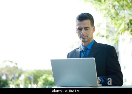 Businessman sitting outdoors, using laptop computer Stock Photo