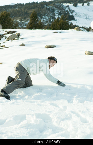 Young man down on all fours in snow, smiling, full length Stock Photo