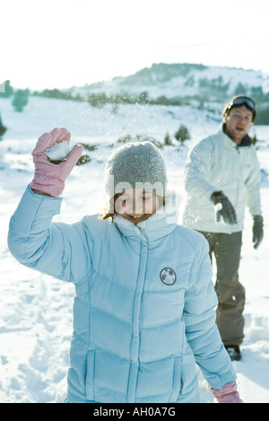 Brother and sister throwing snowballs, girl's eyes closed Stock Photo