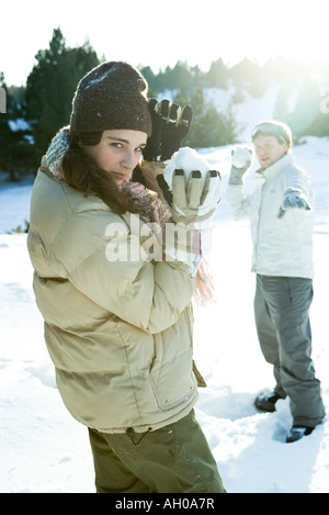 Two young friends holding up snowballs, one looking over shoulder at camera Stock Photo