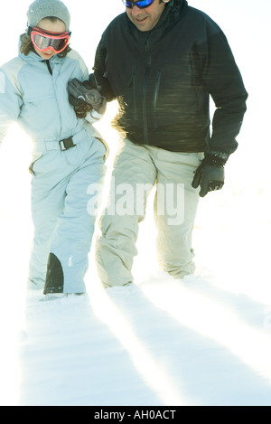 Father and daughter walking in snow together, holding hands, cropped view Stock Photo