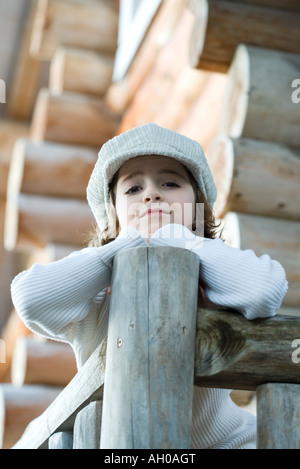 Girl standing on deck of wood cabin, leaning on rail Stock Photo