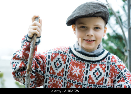 Boy wearing traditional sweater and cap, holding hiking stick Stock Photo