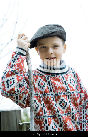 Boy wearing traditional sweater and cap, holding hiking stick Stock Photo
