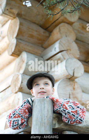 Boy standing on deck of wood cabin, leaning on rail Stock Photo