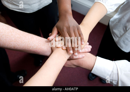 Five office workers showing team work by placing hands on top of each other Stock Photo