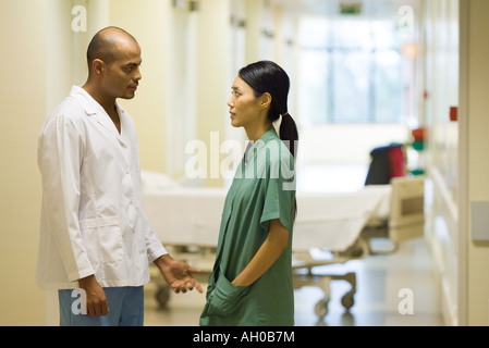 Medical staff standing face to face in hospital corridor, discussing Stock Photo