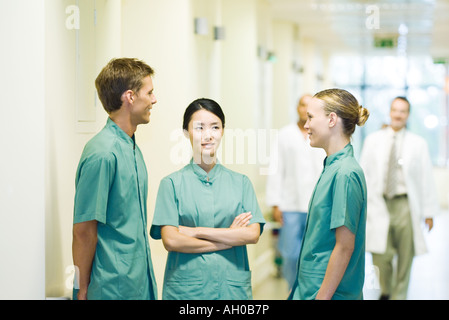 Three medical workers chatting in hospital corridor Stock Photo