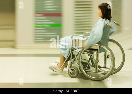 Female patient using wheelchair in hospital corridor, blurred motion Stock Photo