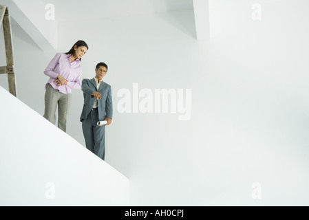 Man and woman standing on mezzanine, man pointing down, low angle view Stock Photo