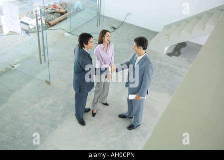 Male real estate agent standing in home interior with young couple, full length, high angle view Stock Photo