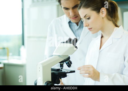 Male and female scientist standing by microscope Stock Photo