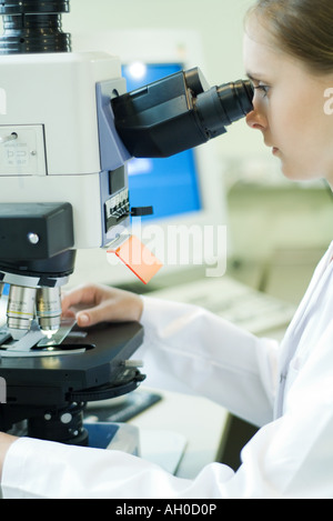 Young female researcher placing slide under microscope Stock Photo