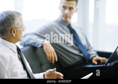 Two male business associates, sitting on sofa, talking Stock Photo