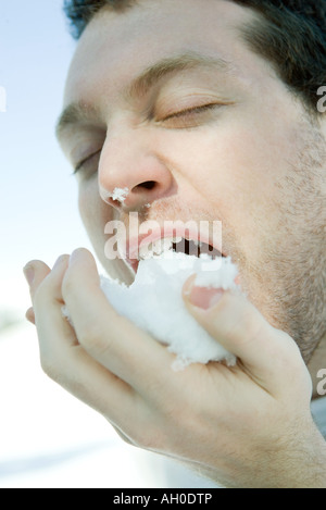 Young man eating snow, eyes closed, close-up Stock Photo