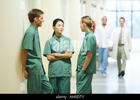 Three young medical colleagues standing in hallway, having discussion Stock Photo