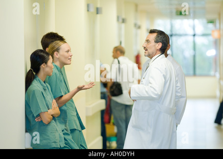 Young hospital staff chatting with mature male doctor, side view Stock Photo