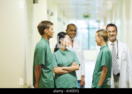 Group of medical staff standing in hallway, chatting, two looking at camera Stock Photo