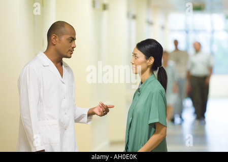 Medical staff standing  face to face in hallway, discussing Stock Photo