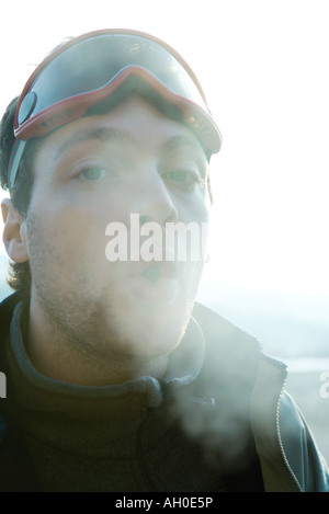 Young man breathing out into cold air Stock Photo