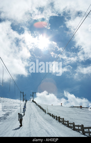 Young skiers using ski lift on hill. rear view, in the distance Stock Photo