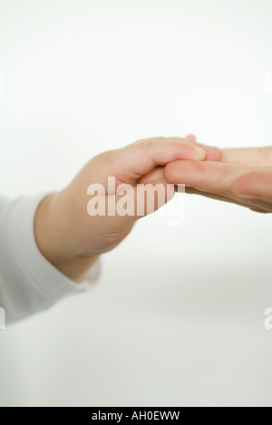 Baby holding adult's fingers, cropped view Stock Photo