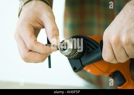 Man adjusting drill bit, cropped view of hands Stock Photo