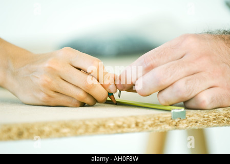 Couple measuring wood, cropped view of hands Stock Photo