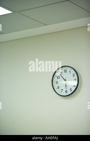 Clock hanging on wall under fluorescent light Stock Photo