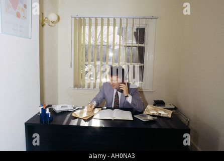 Man At Desk With Old Mobile Phone Stock Photo
