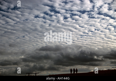 Three people walk beneath Altocumulus clouds (known as a mackerel sky) Stock Photo