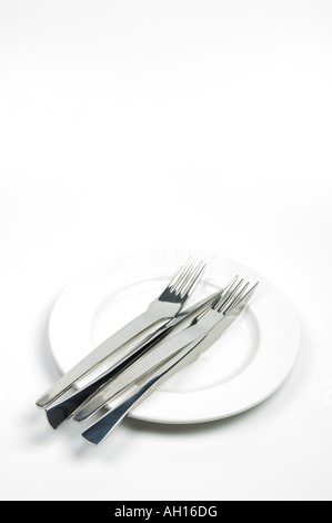 Knives and forks on a white plate - table settings Stock Photo
