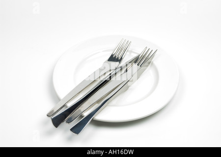 Knives and forks on a white plate - table settings Stock Photo