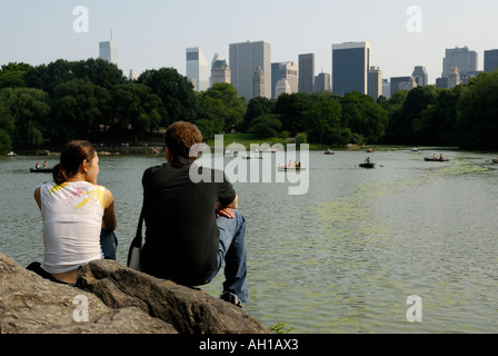 Young couple looking at Central Park Lake with boaters and New York City skyline, Manhattan Stock Photo