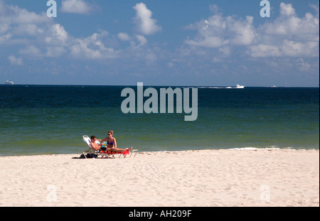 Man and Woman Sit in Lounge Chairs On Beach Ft Lauderdale Florida USA Stock Photo