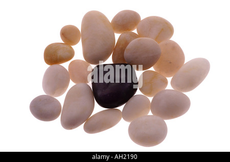 Smooth white beach stones surrounding one black stone, silhouette on white background Stock Photo