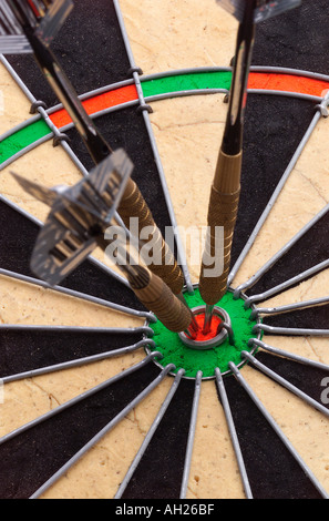 dart stuck in the bullseye of a dart board silhouetted on white background Stock Photo