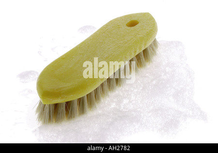 yellow scrub brush wth soap suds silhouetted on white background Stock Photo