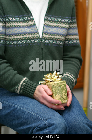 Hands holding wrapped Christmas gift over kraft paper with wide copy ...