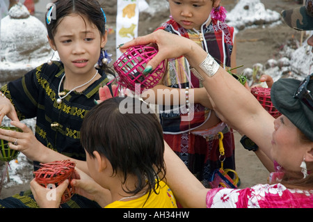 Woman and children gaining good karma by setting caged bird free near sand stupas on the bank of the Mekong River Luang Prabang Stock Photo