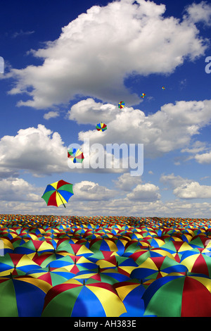 vast sea of umbrellas against blue summer sky with a line of umbrellas flying away rain Stock Photo