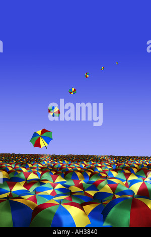 vast sea of umbrellas against blue summer sky with a line of umbrellas flying away rain Stock Photo