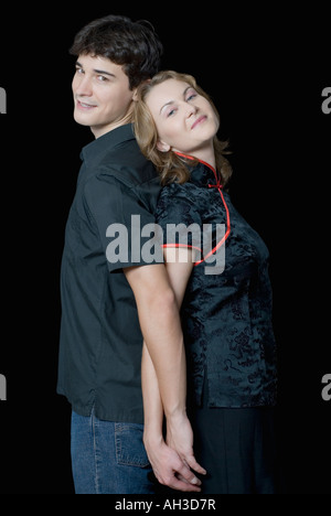 Side profile of a young couple standing back to back Stock Photo