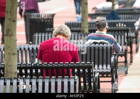 Men sitting outside on metal city benches Stock Photo